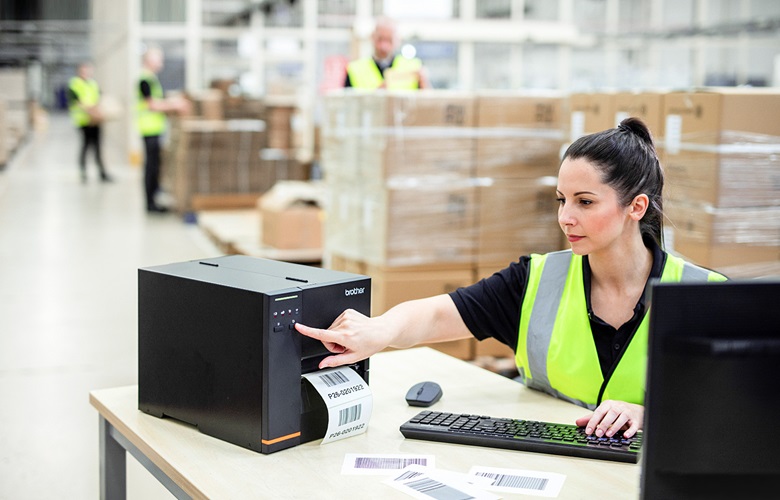 Logistikmitarbeitsbedient tj-etikettendrucker, ein tisch sitenz in lagerhalle